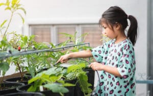 Petite fille arrosant ses cultures sur le balcon